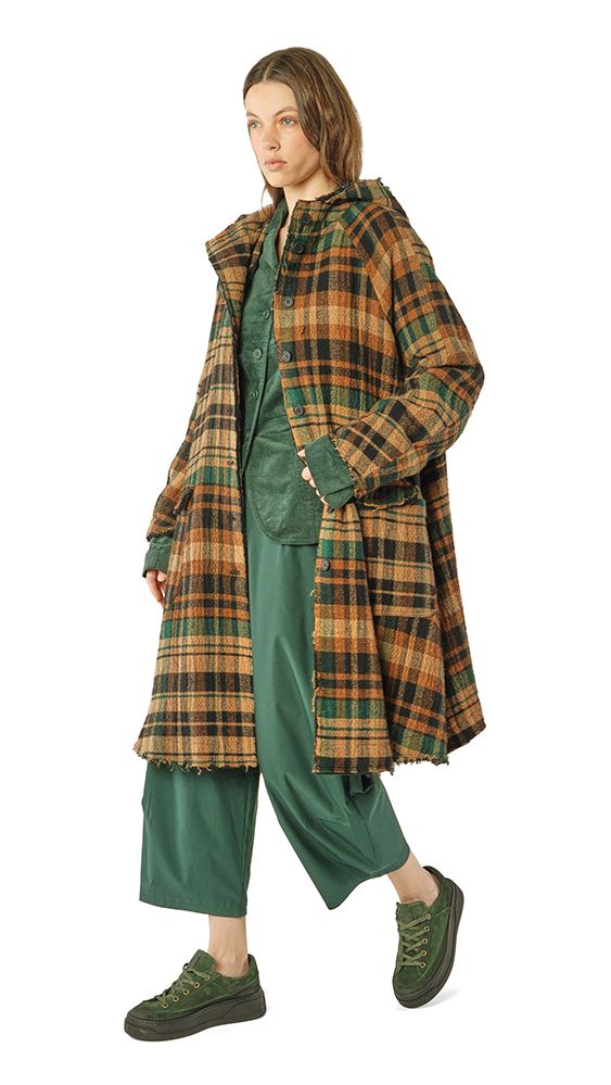 Person trägt oversized Plaid-Mantel mit grünem Kleid und weiten Hosen, grüne Sneaker.