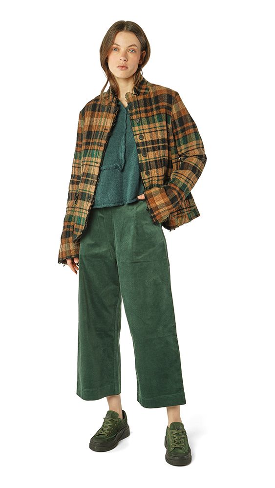 Person trägt grünen oversized Blazer, dunkle weite Cordhose und grüne Sneakers mit tealfarbenem Top.