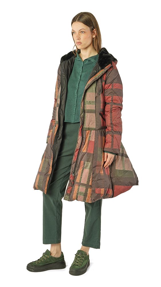 Frau trägt bunte Patchwork-Jacke mit grünem Top und dunklen Hosen, grüne Sneakers.