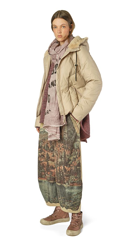 Person trägt beige Daunenjacke, bunte weite Hose und robuste Schuhe, lässiger Streetwear-Look.