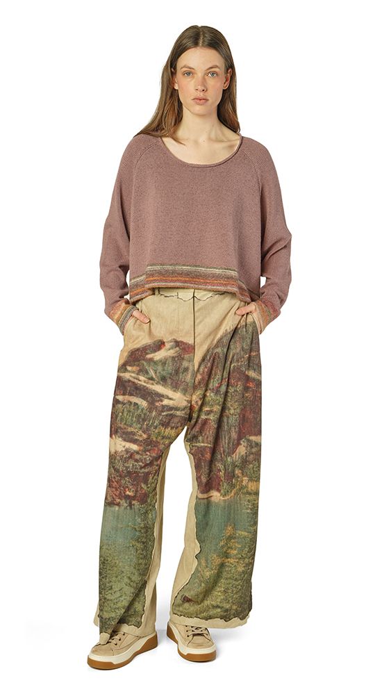 Person trägt oversized Pullover mit farbenfrohen, zerrissenen Patchwork-Pantalons und Sneakern.