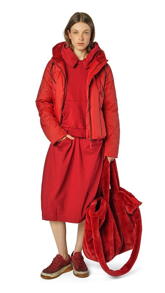 Frau trägt langes, rotes Überziehmantel-Kleid mit Kapuze und hält rote Tasche, bequeme Schuhe.