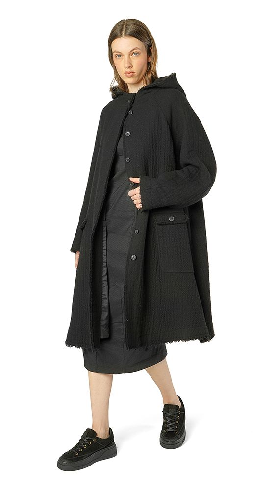 Schwarzer oversized Mantel mit Paillettenbesatz, kombiniert mit kurzem Kleid und Sneakern.