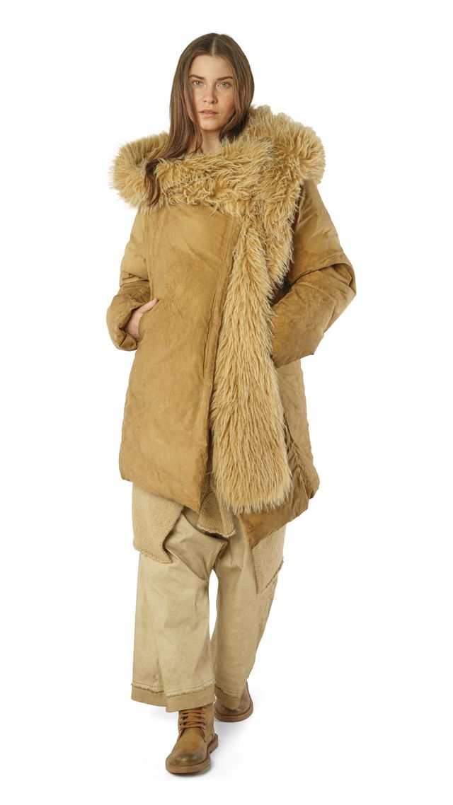 Frau trägt beige Daunenmantel mit Fellkragen und weiten Hosen, steht lässig stehend.