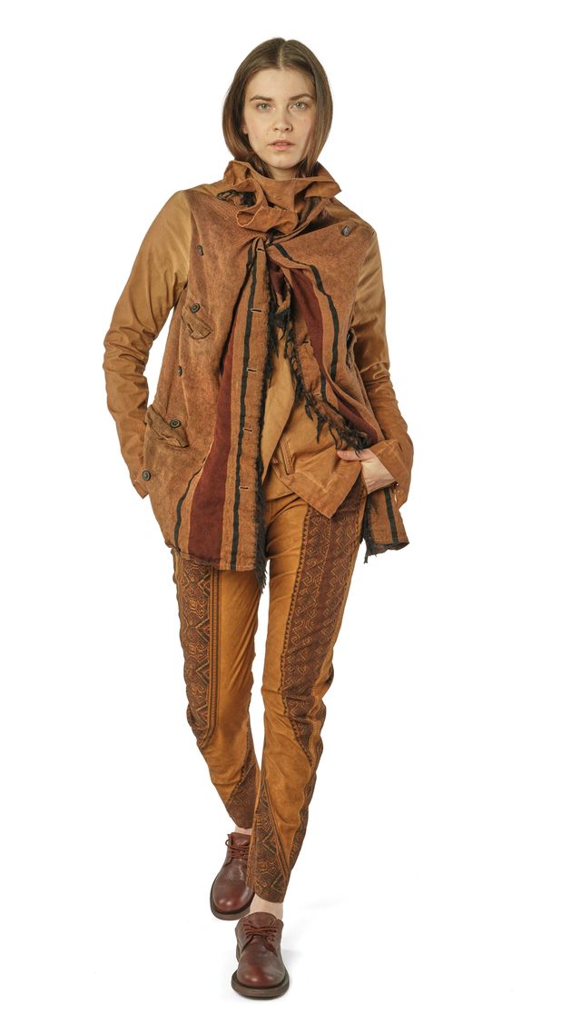 Frau trägt eleganten, gemusterten Overall mit Schal und braunen Stiefeln, stilvoll und lässig.