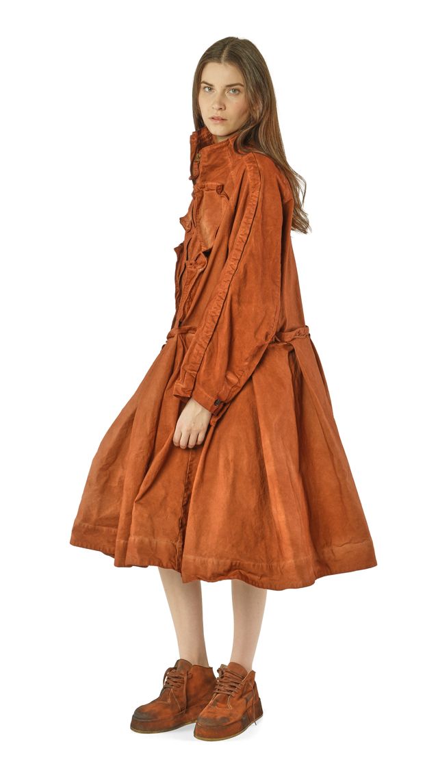 Frau trägt langes, rustikales, orangefarbenes Kleid mit weitem Rock und braunen Stiefeln.