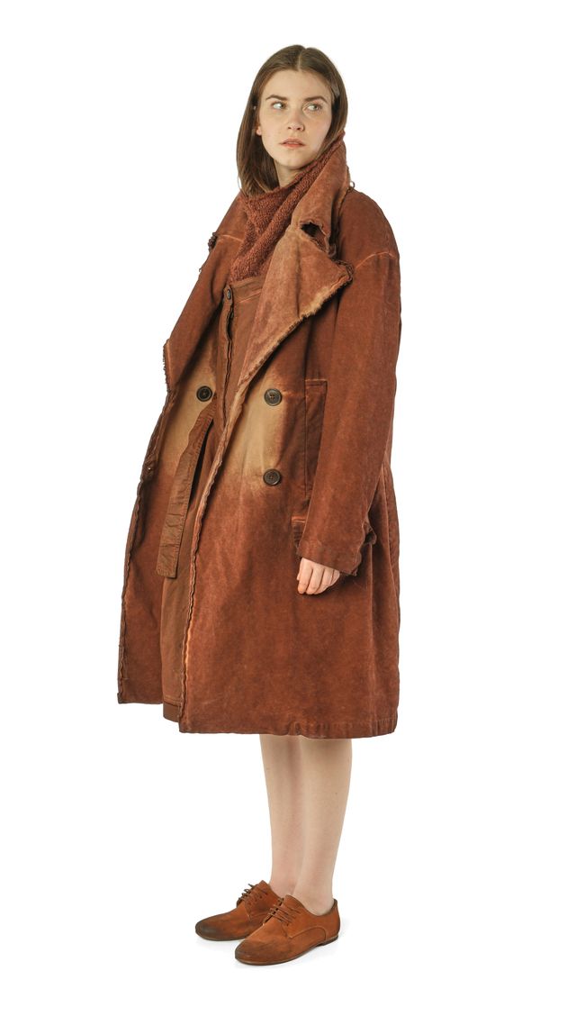 Frau trägt langen, braunen Süttenmantel mit Knöpfen und bequemen Schuhen, elegant und warm.
