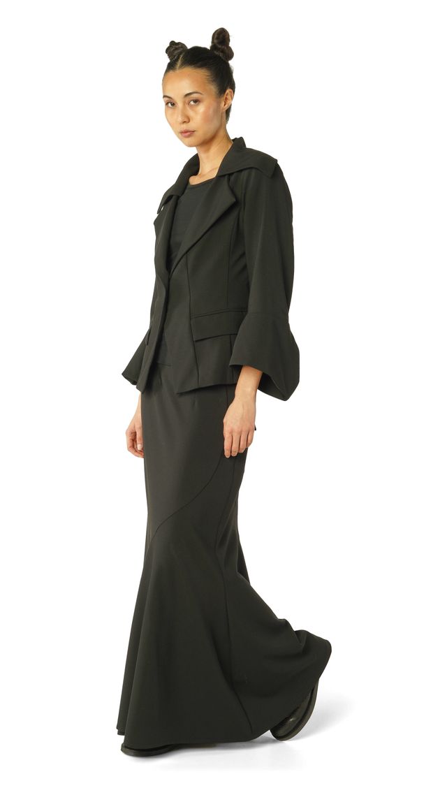 Elegante Frau im langen schwarzen Kleid mit oversized Blazer, schlicht und modern.